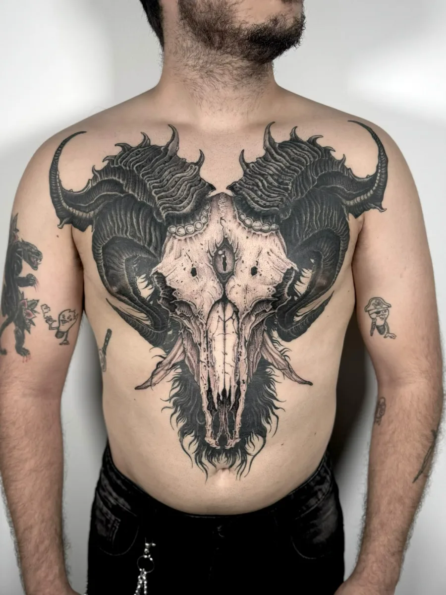 Tatuaje blackwork de un cráneo de carnero con cuernos que cubre todo el pecho, hecho en Santos Castelldefels